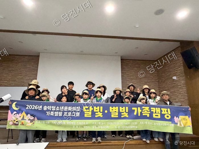 참가자들이 가족캠핑 프로그램 현수막을 들고 기념 촬영을 하고 있다.