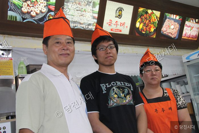 식당을 운영하는 세 사람이 모여 주방에서 포즈를 취하고 있다.