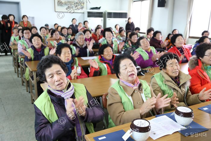 노인들이 실내에 모여 박수를 치며 즐거워하고 있다.