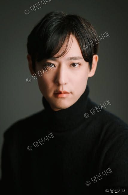 단정한 차림의 남성이 정면을 바라보며 서 있다.