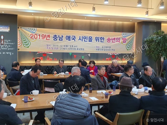 사람들이 모여 테이블에 앉아 2019년 송년의 밤 행사를 하고 있다.