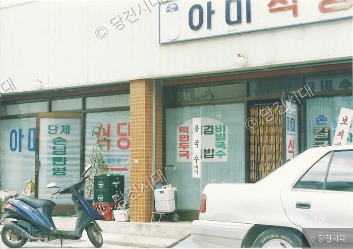 당진의 어느 한 식당 앞 길가에 스쿠터 한 대와 승용차가 주차되어 있다.
