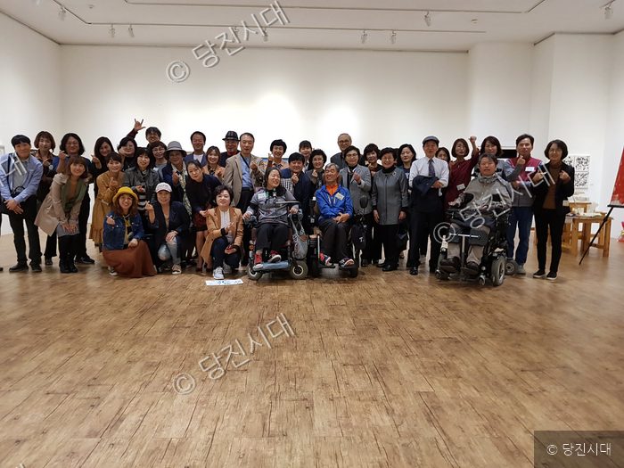 장애인과 지역 주민들이 함께 '아름다운 동행전' 전시회를 관람하며 기념 촬영을 하고 있다.