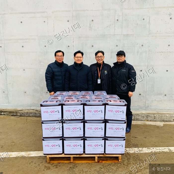 네 명의 남성이 김장김치 상자들 뒤에서 포즈를 취하고 있다.