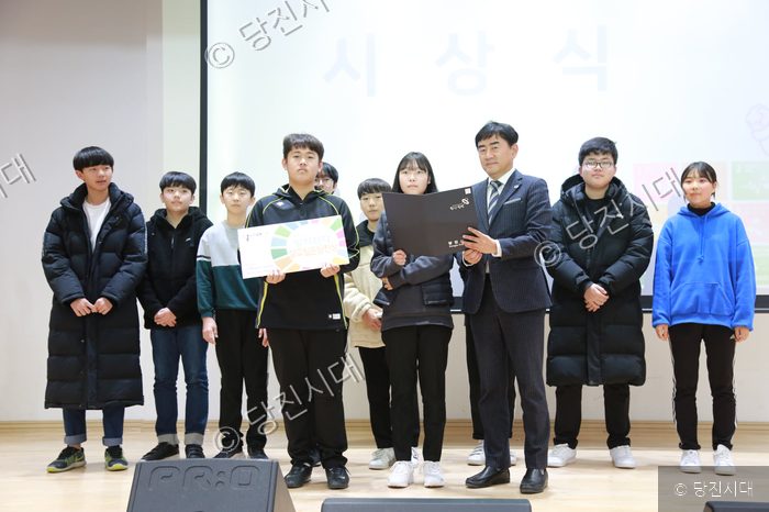 한 남성이 청소년들에게 상장을 전달하며 기념사진을 촬영하고 있다.