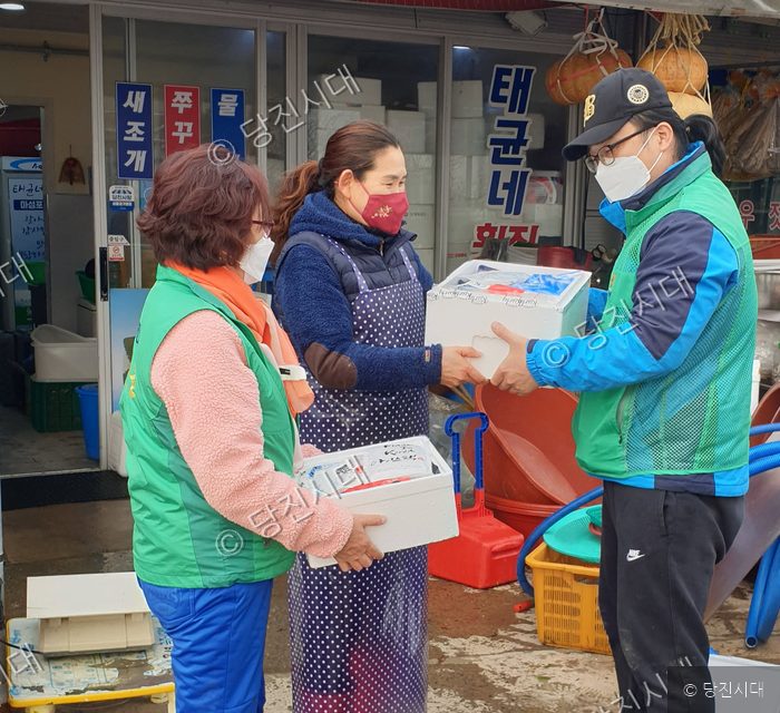자원봉사자들이 상인에게 물품이 담긴 상자를 전달하고 있다.