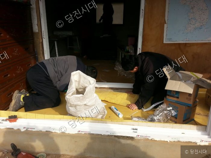 두 사람이 집수리 현장에서 내부 작업을 하고 있다.