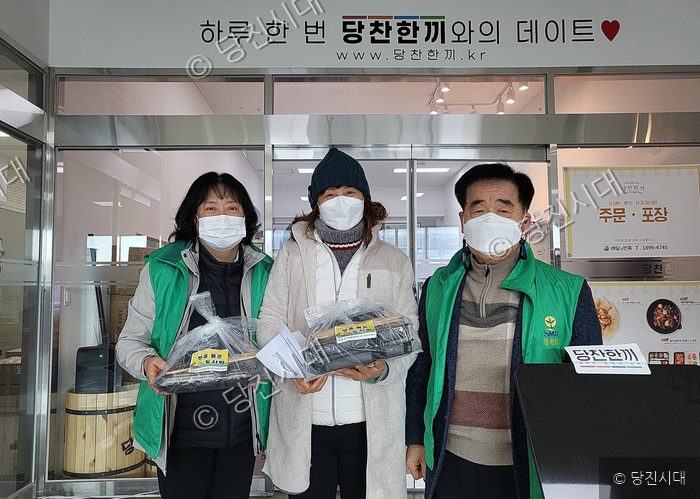 세 명의 주민이 봉사 활동을 위해 도시락을 들어 보이고 있다.