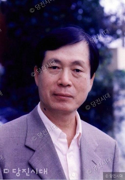 김근당 작가가 밝은 표정으로 카메라를 정면으로 응시하고 있다.