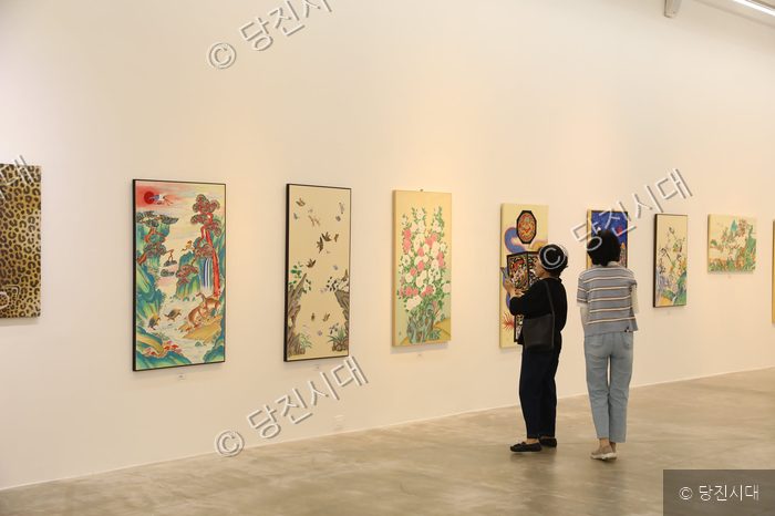 관람객들이 미술관에서 전통 민화 작품들을 감상하고 있다.