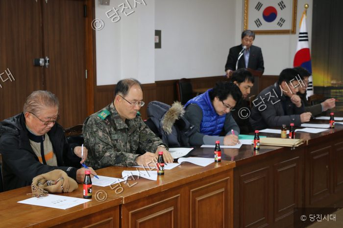 참석자들이 회의 테이블에 앉아 문서를 보고 있다.