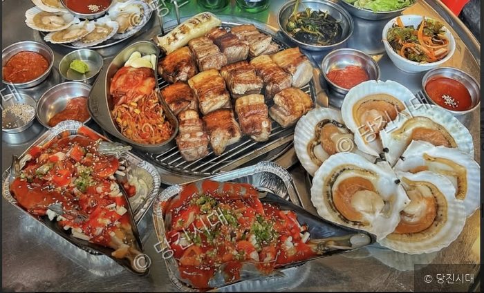 당진의 한 당진시 청룡길 66에서 연탄불 고기와 신선한 해산물이 푸짐하게 차려져 있다.