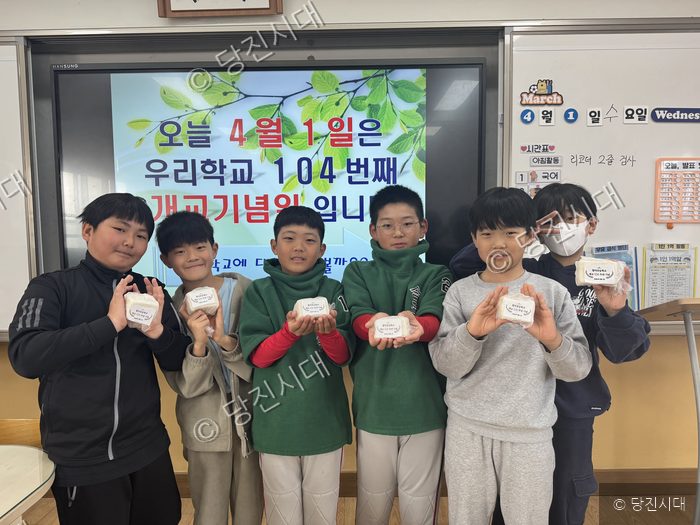 합덕초등학교 학생들이 개교 104주년을 맞아 기념 떡을 들고 기념 촬영을 하고 있다.