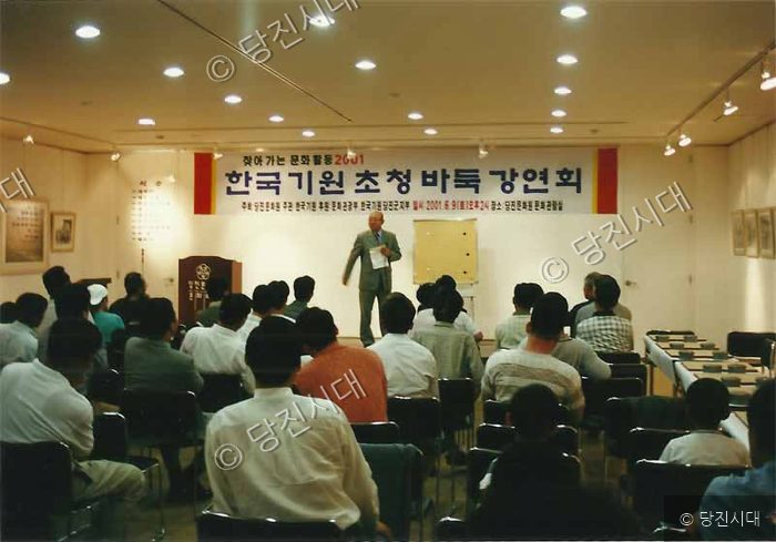 강연자가 바둑 강연회에서 청중을 향해 설명하고 있다.