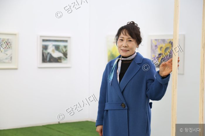 김윤숙 작가가 미술 전시회장에서 포즈를 취하고 있다.