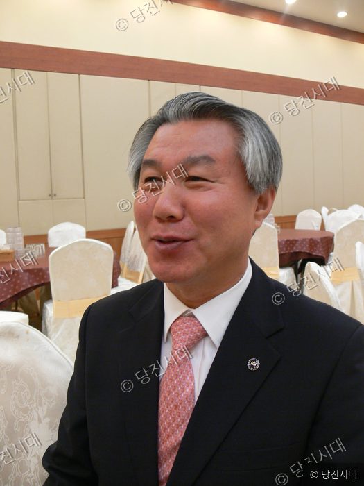 정장 차림의 송명호 씨가 미소를 지으며 카메라를 바라보고 있다.