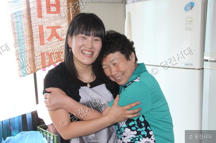 어머니와 며느리가 다정하게 포옹하며 환하게 웃고 있다.