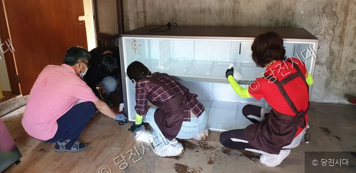 주민들이 냉장고를 청소하며 봉사 활동을 하고 있다.