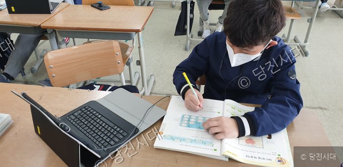 한 학생이 교실에서 태블릿을 보며 공부하고 있다.