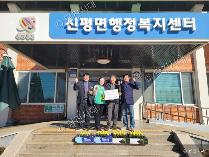 지역 박종환 이장 등이 행정복지센터에서 들기름을 기탁하고 기념 촬영을 하고 있다.