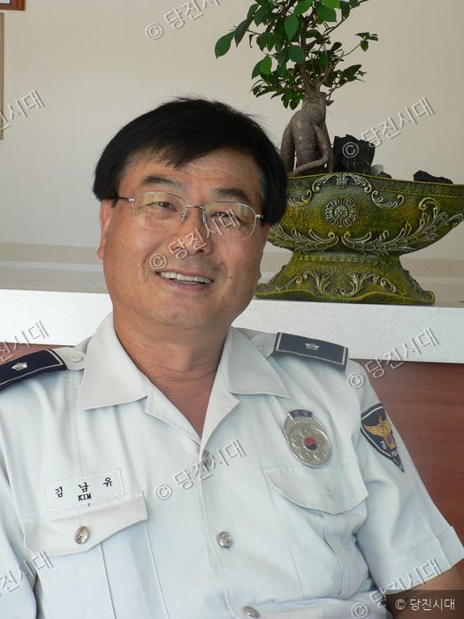 김남유가 경찰 제복을 입고 카메라를 향해 미소 짓고 있다.