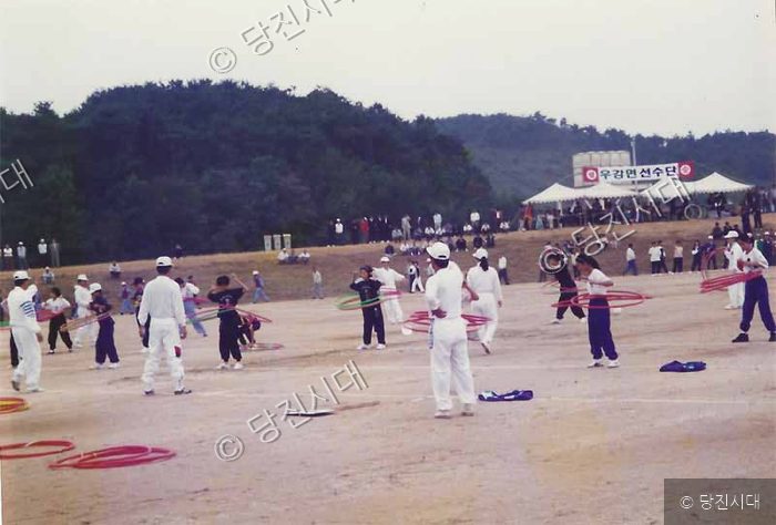 제28회 군민체육대회에서 참가자들이 운동장에서 훌라후프 경기를 하고 있다.