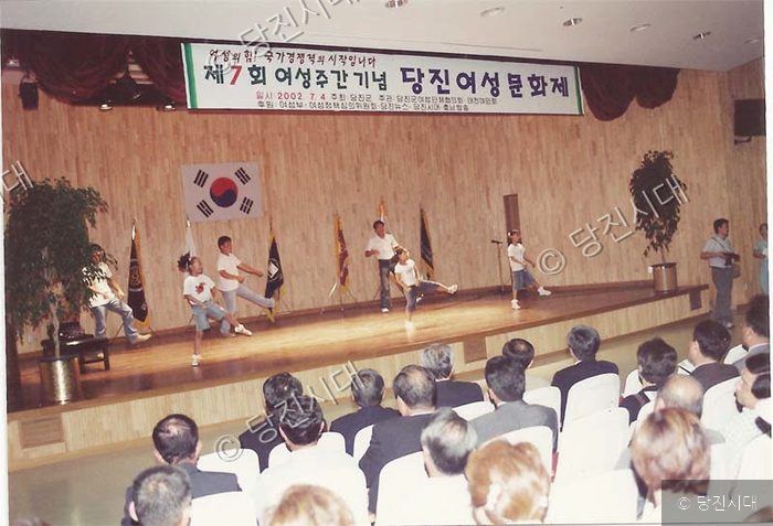무대에서 어린이들이 춤을 추고 관객들이 바라보고 있다.