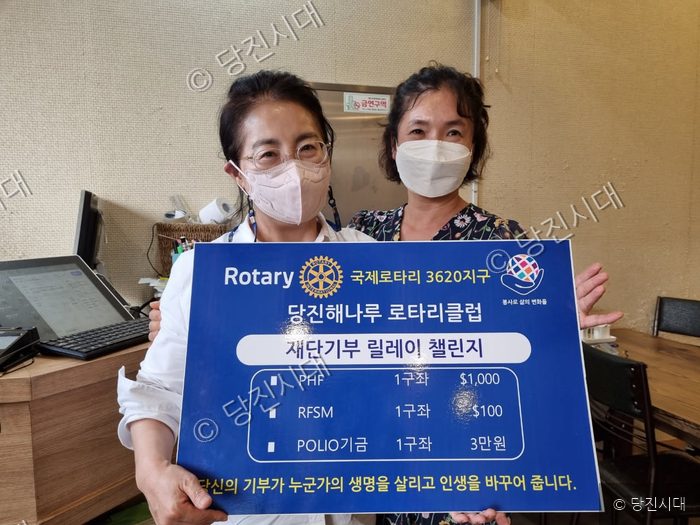 두 사람이 재단기부 릴레이 챌린지 피켓을 들고 포즈를 취하고 있다.