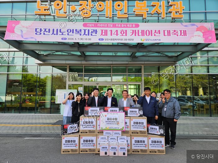 당진시노인복지관 앞에서 관계자들이 카네이션 대축제 후원 물품과 함께 기념 촬영을 하고 있다.