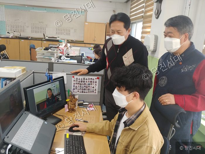 세 사람이 학교 사무실에서 온라인 개학 관련 컴퓨터 화면을 살펴보고 있다.