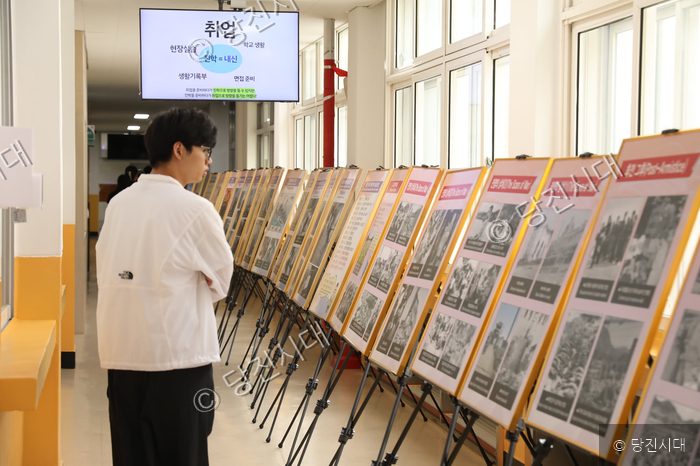 한 학생이 복도에 설치된 역사 사진전 패널들을 둘러보고 있다.