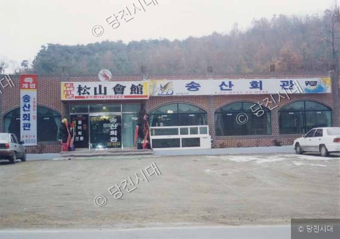 송산회관 건물의 전경과 앞 주차장 모습이다.