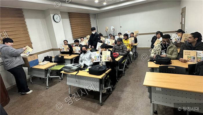 외국인 근로자들이 교실에서 책을 들고 교육을 받고 있다.