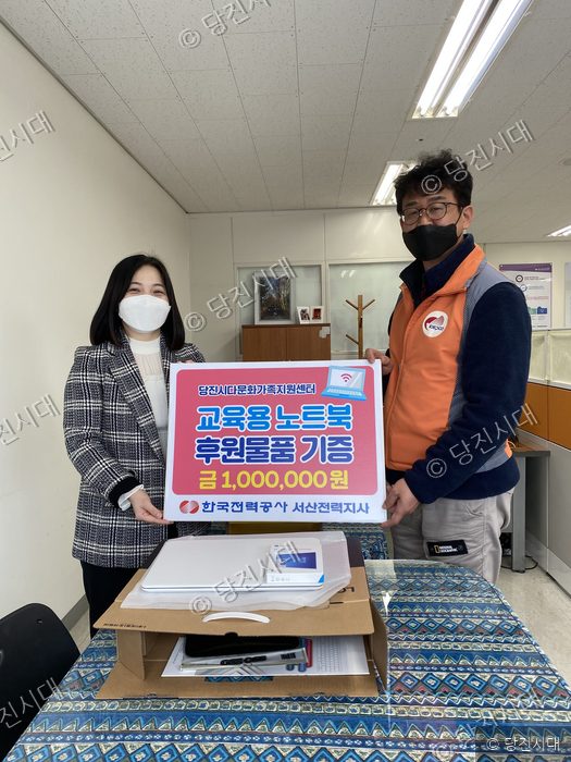 두 사람이 다문화가정을 위한 노트북 후원 물품을 기증하고 있다.