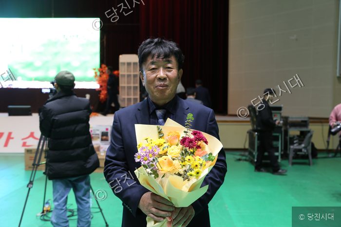행사장에서 오성환 시장이 꽃다발을 들고 미소 짓고 있다.