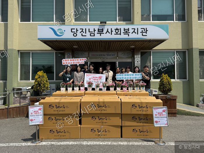당진시남부사회복지관 앞에서 관계자들이 카네이션 후원 기념 촬영을 하고 있다.