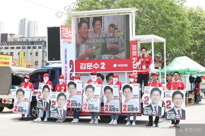 국민의힘 후보 유세 차량 앞에서 지지자들이 피켓을 들고 선거 유세를 하고 있다.
