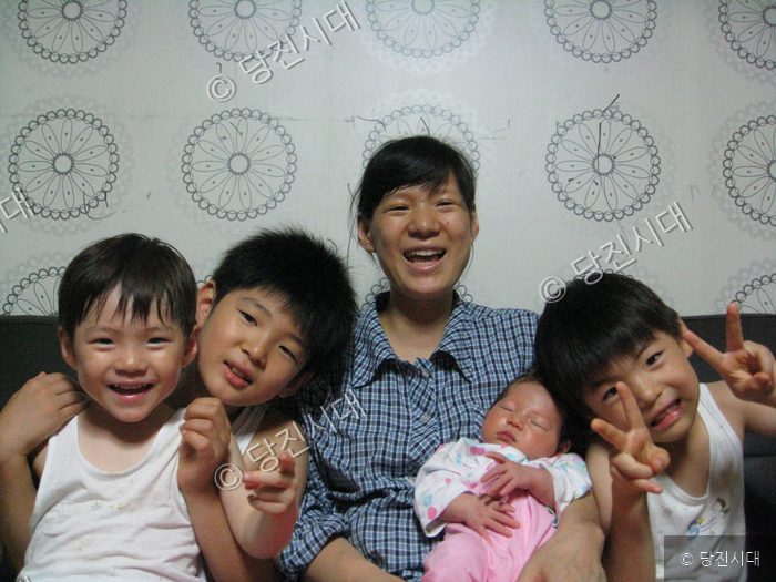 어머니와 아들 셋, 그리고 갓 태어난 막내딸이 함께 환하게 웃고 있다.