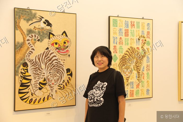 민화 협회 이숙경 회장이 자신의 민화 작품 앞에 서 있다.