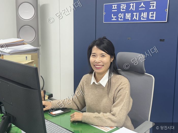 박미정 복지사가 사무실 책상에 앉아 미소 짓고 있다.