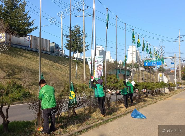 주민들이 도로변에서 새마을기 등 깃발을 정비하고 있다.