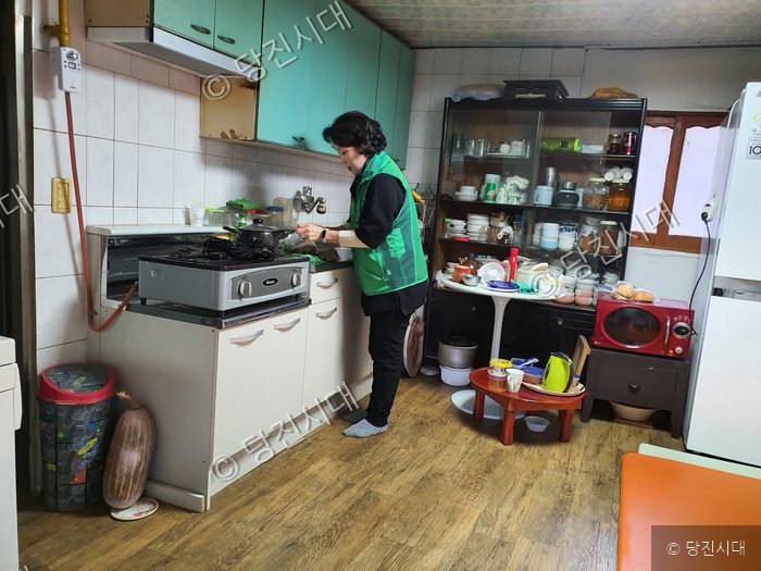 여성이 주방에서 음식 준비 봉사 활동을 하고 있다.