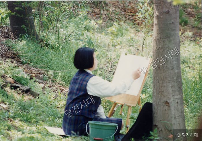 한 여학생이 당진JC사생대회 현장에서 야외 이젤을 놓고 그림을 그리고 있다.