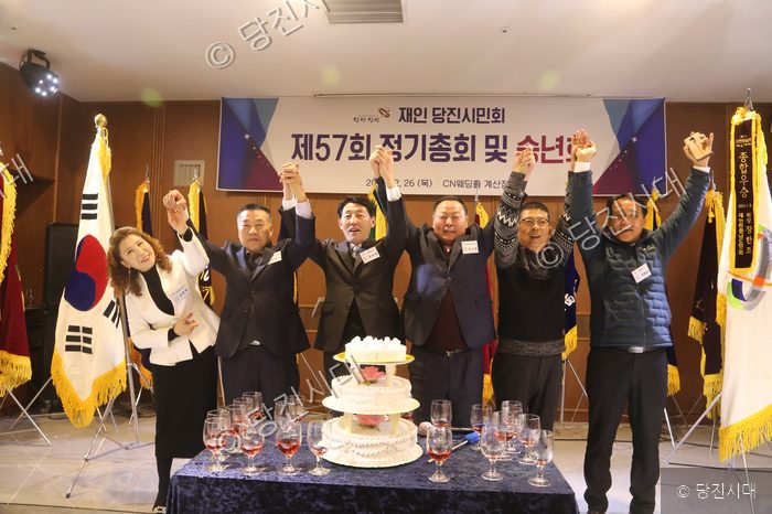 당진시민회 회원들이 정기총회 및 송년회에서 손을 맞잡고 기념촬영을 하고 있다.
