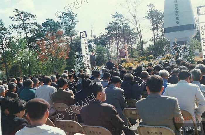 주민들이 야외에서 엄숙한 분위기로 추모 행사를 거행하고 있다.