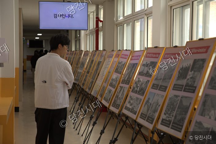 한 남학생이 학교 복도에 설치된 전쟁 역사 사진전을 관람하고 있다.