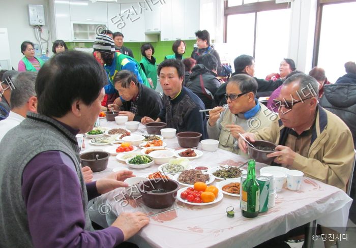 지역 주민들이 모여 앉아 음식을 나누며 식사를 하고 있다.