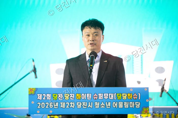 한 남성이 청소년 축제 무대에서 마이크를 잡고 발언하고 있다.