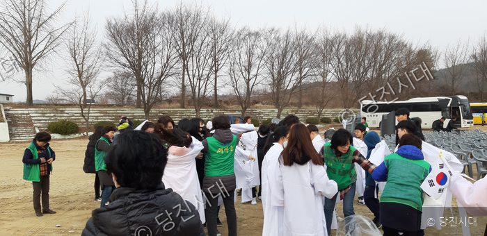 야외에서 주민들과 새마을지도자들이 흰색 의복과 소품을 정리하고 있다.