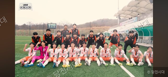 신평중학교 축구부 선수들과 코칭스태프가 운동장에서 기념 촬영을 하고 있다.